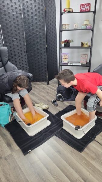 a boy and girl enjoying a foot detox with both feet in water tubs