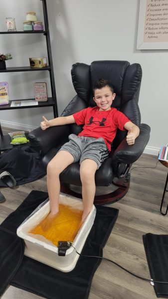 a boy sitting in a chair with a foot bath